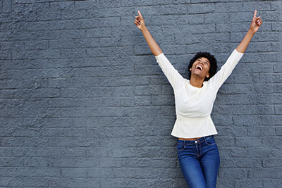 Cheerful african woman with hands raised pointing up